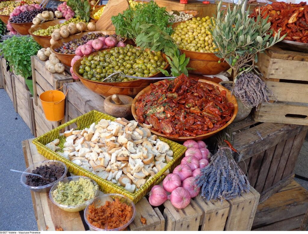 Divers produits frais du marché en Provence : olives, tomates séchées et herbes aromatiques.