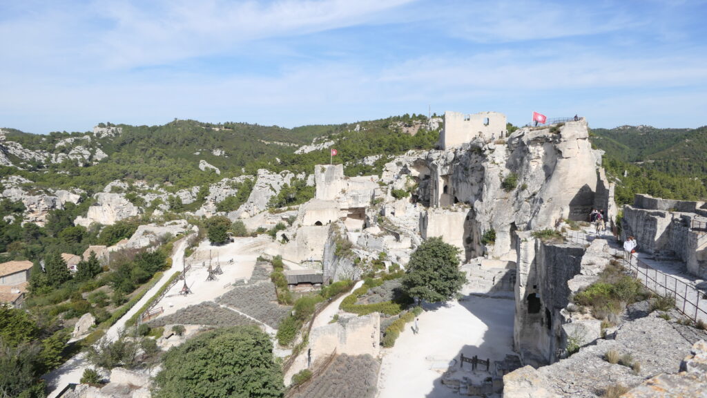 Ruines du Château des Baux-de-Provence surplombant un paysage verdoyant avec des visiteurs en promenade.