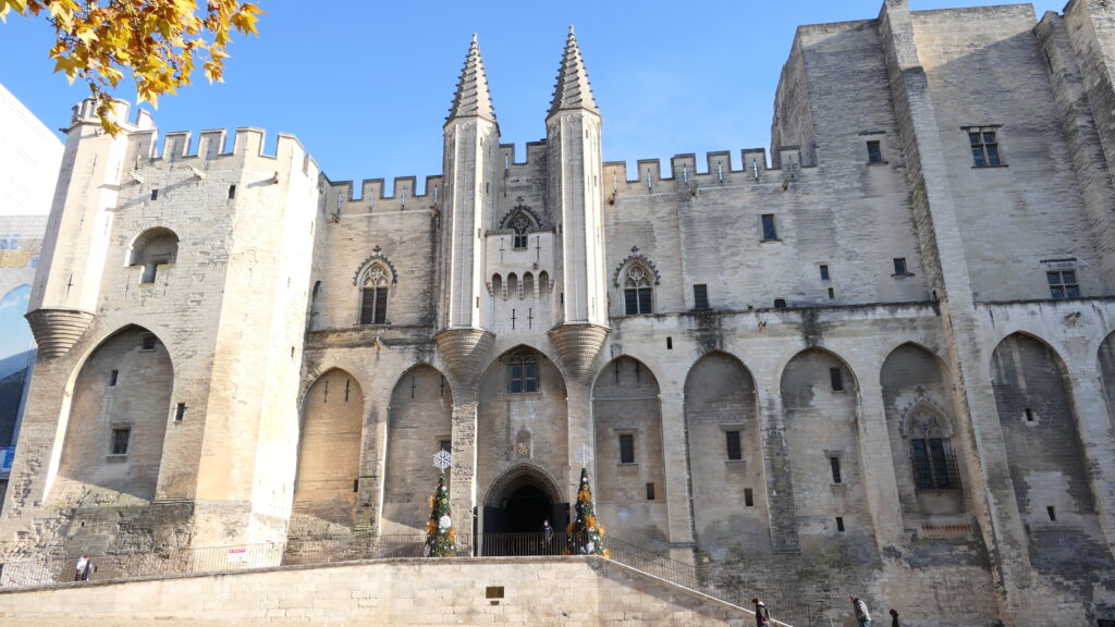 Vue du Palais des Papes à Avignon, avec ses tours et ses façades en pierre sous un ciel clair d'hiver.