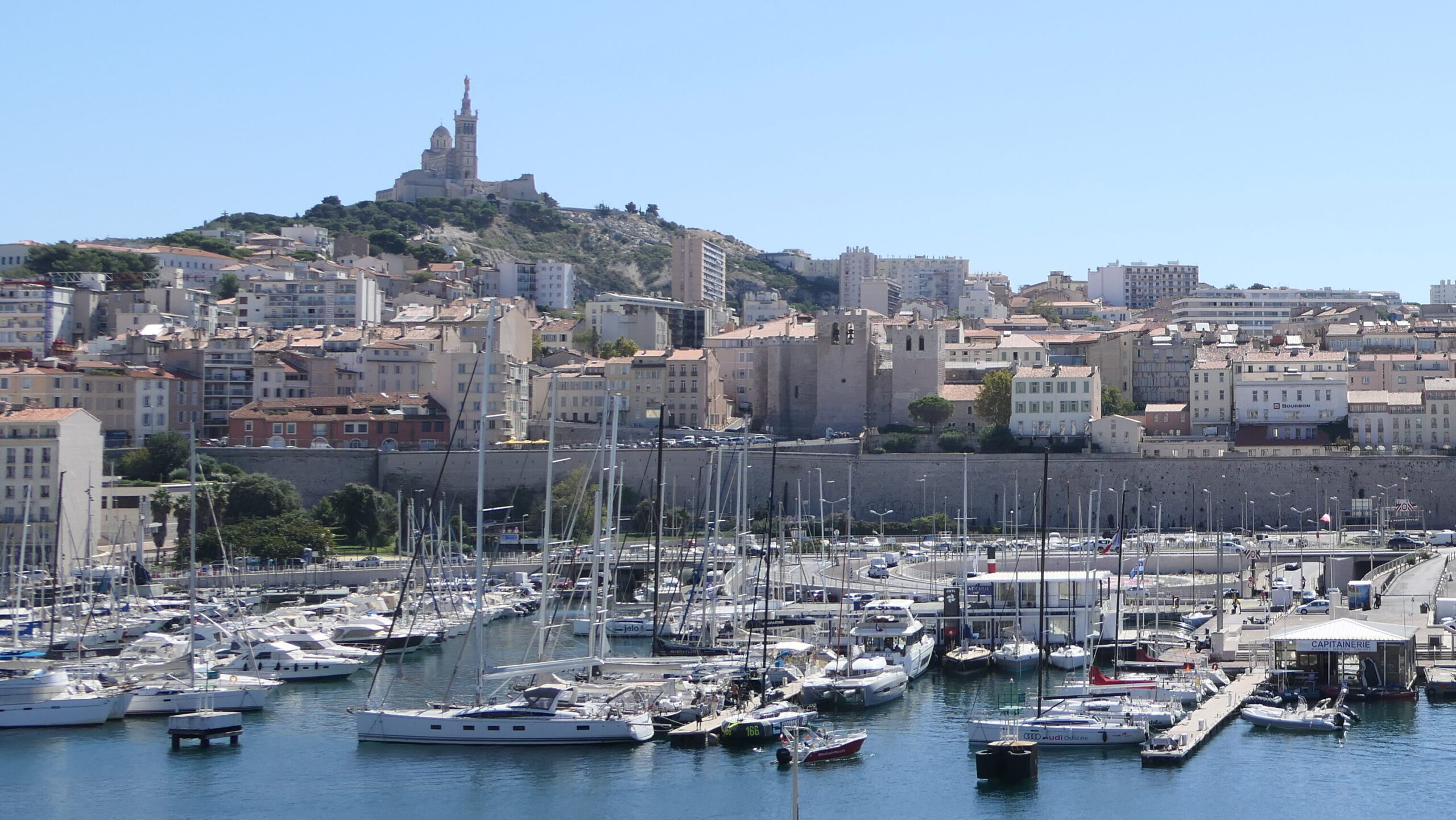 Vieux-Port de Marseille avec bateaux amarrés et Notre-Dame de la Garde en hauteur.