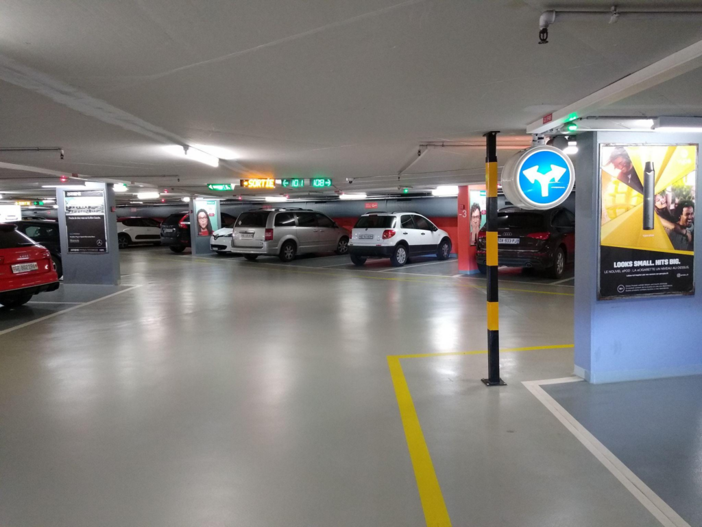 Intérieur d'un parking souterrain bien éclairé à Marseille montrant plusieurs voitures stationnées et des panneaux indicateurs