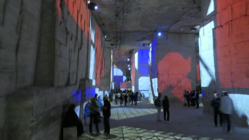 Visiteurs admirant une exposition immersive aux Carrières de Lumières.