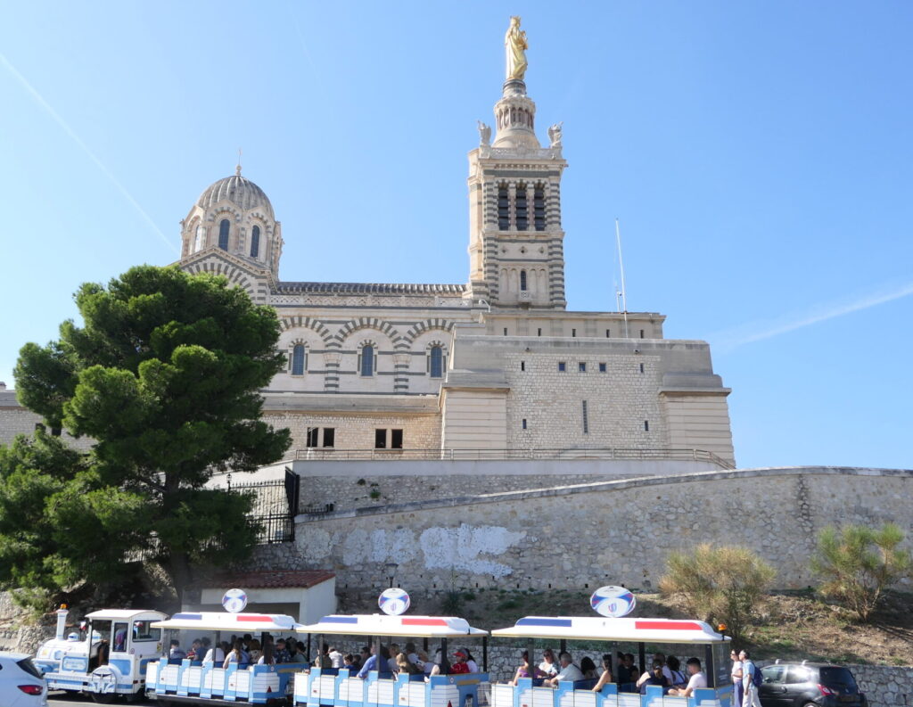 Petit train touristique devant la Basilique Notre-Dame de la Garde à Marseille.